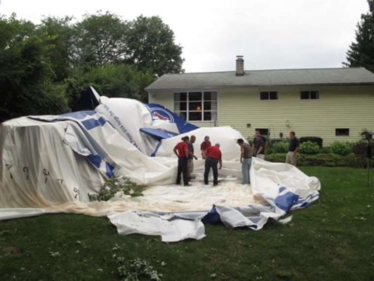 Crews take apart a blimp that broke free of its moorings at an airport and landed in a resident's backyard on Sunday in Worthington, Ohio. 